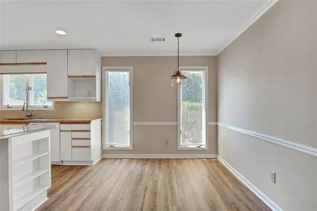 a view of an empty room with a kitchen and a window