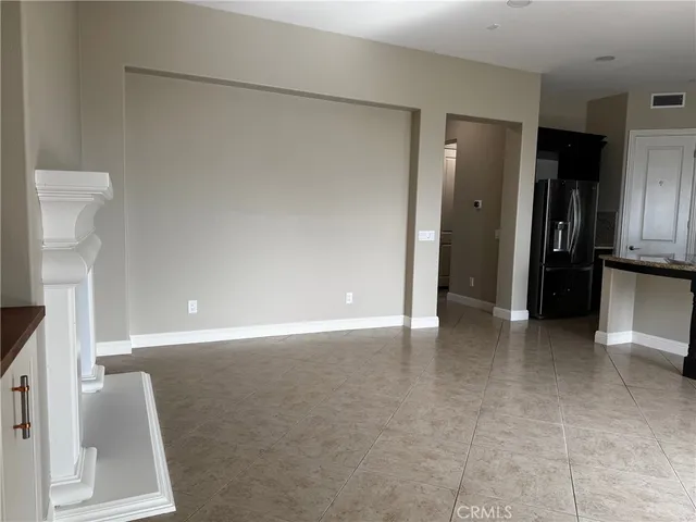a view of an empty room with kitchen and a window