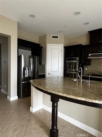 a kitchen with stainless steel appliances granite countertop a sink and a refrigerator