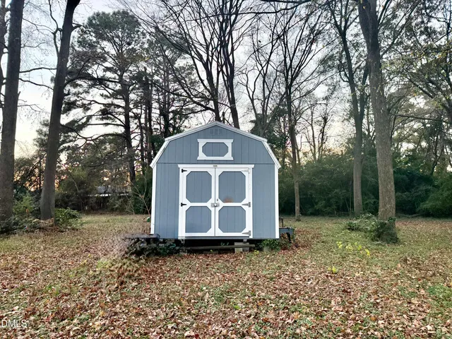 a view of a white house with a large tree and wooden fence