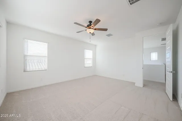 an empty room with windows and fan chandelier fan