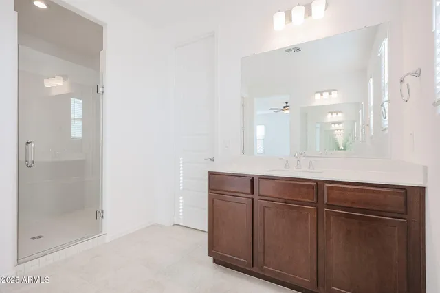 a bathroom with a granite countertop sink two mirror and shower