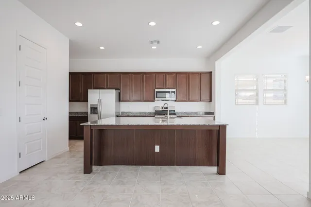 a room with kitchen island granite countertop a sink and a refrigerator