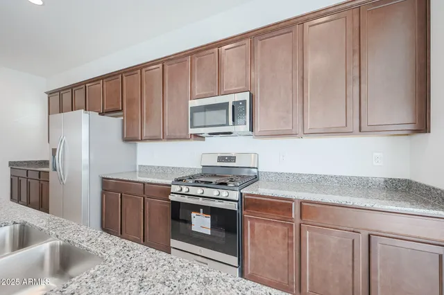 a kitchen with granite countertop a sink stove and refrigerator