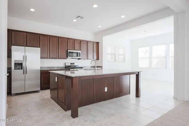 a kitchen with stainless steel appliances granite countertop a refrigerator and a stove top oven