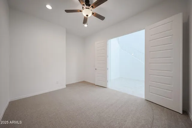 an empty room with closet and a chandelier fan