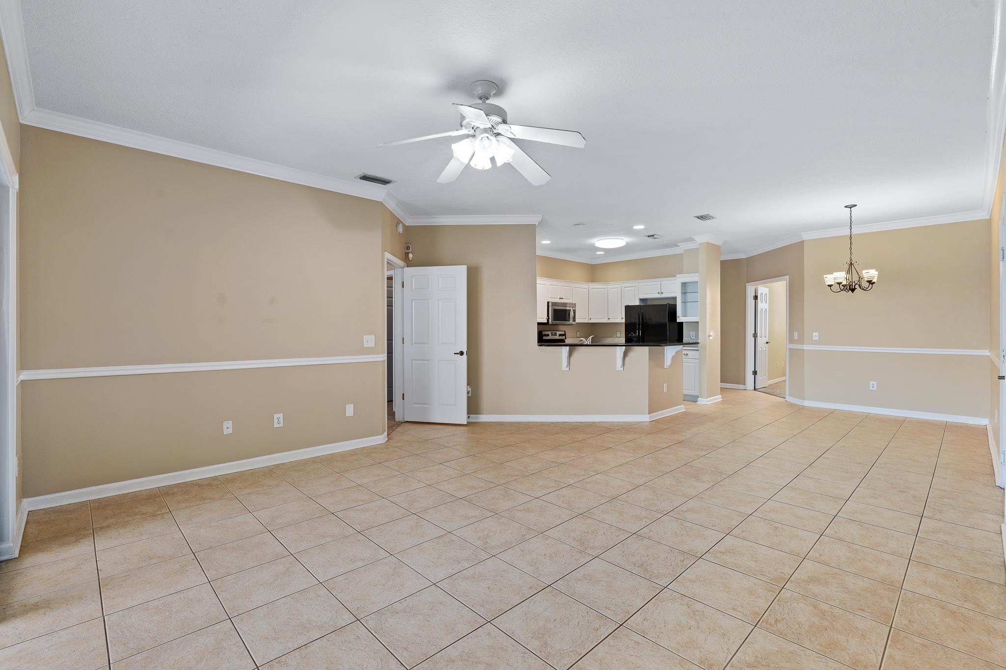 3425 Haley Pointe Road St. Augustine, FL 32084 - Photo 16 of 71 Unfurnished living room with a ceiling fan, crown molding, hanging lights, and light tile patterned flooring