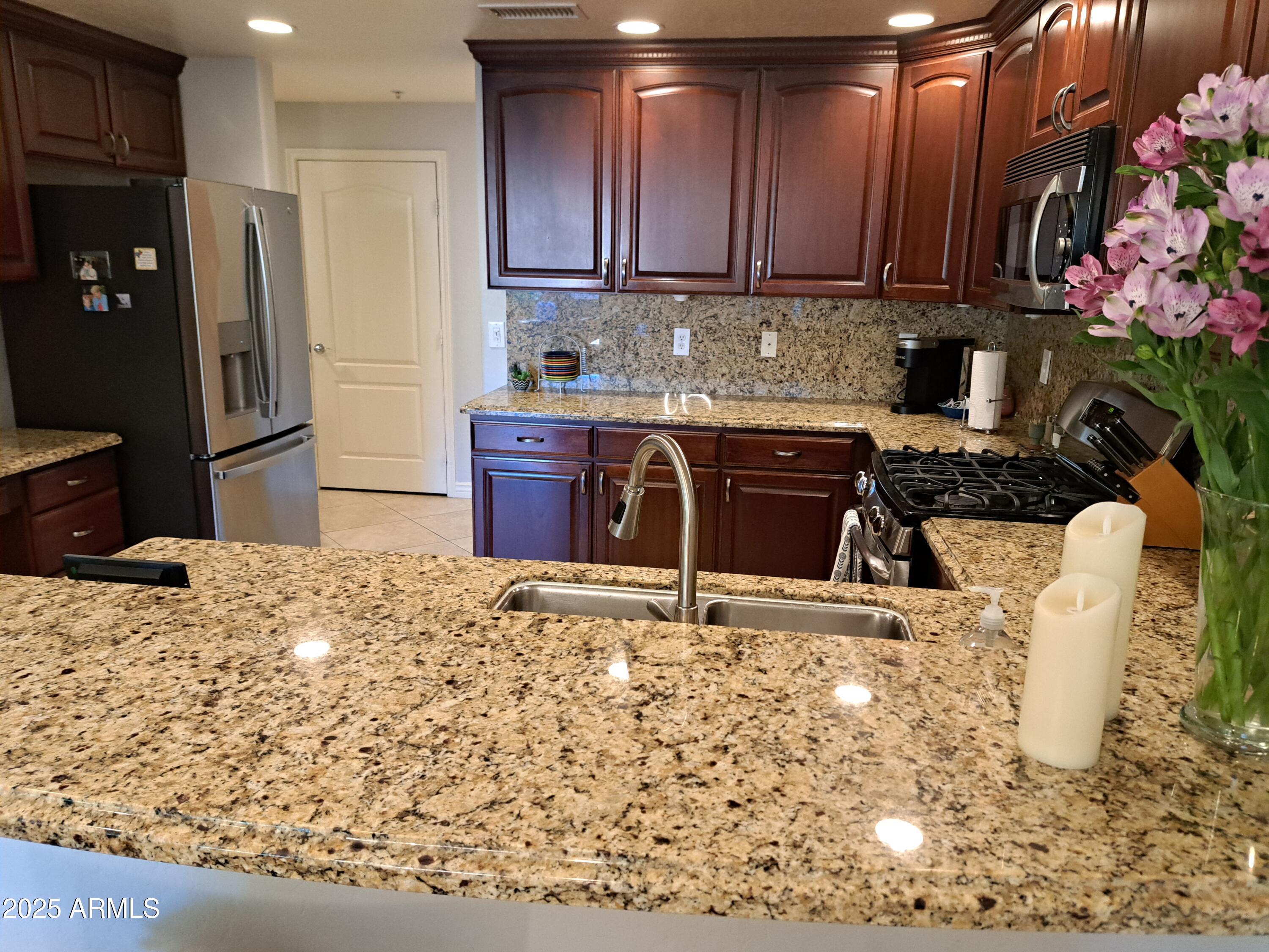 21320 North 56th Street, Unit 1163 Phoenix, AZ 85054 - Photo 12 of 48 a kitchen with stainless steel appliances kitchen island granite countertop a refrigerator and a sink