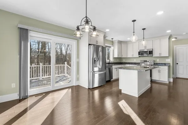 a kitchen with stainless steel appliances kitchen island granite countertop a refrigerator a oven a large island with wooden floor and cabinets