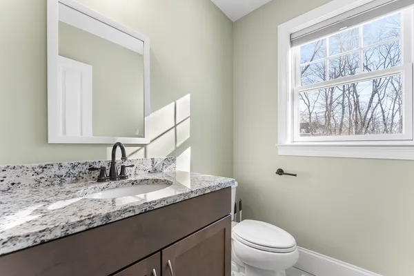 a bathroom with a granite countertop toilet sink and mirror