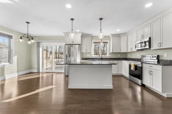a kitchen with stainless steel appliances granite countertop a refrigerator a sink dishwasher a stove and white cabinets with wooden floor