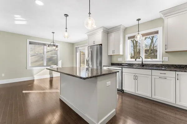 a kitchen with stainless steel appliances granite countertop a sink a stove and a wooden floors