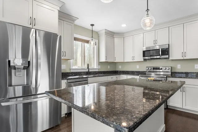 a kitchen with stainless steel appliances granite countertop a refrigerator a sink a stove and cabinets