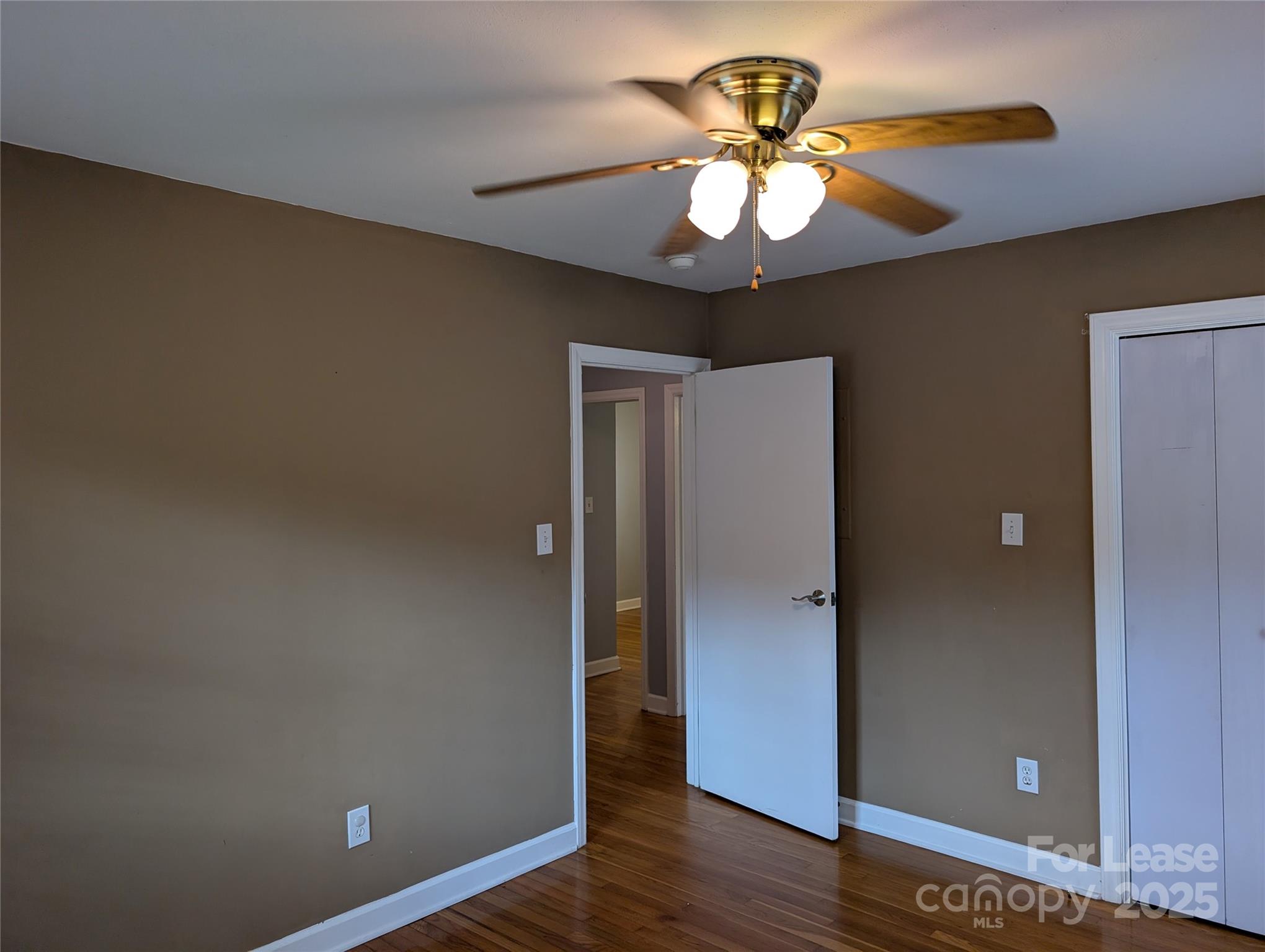 155 Hamptons Cove Road Troutman, NC 28166 - Photo 16 of 22 an empty room with wooden floor and chandelier fan