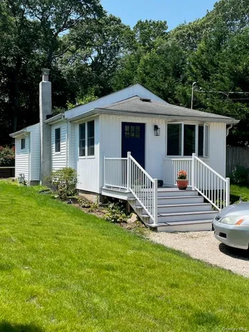 a white house that has a small yard and wooden fence