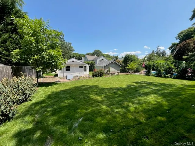 a view of a white house with a big yard and large trees