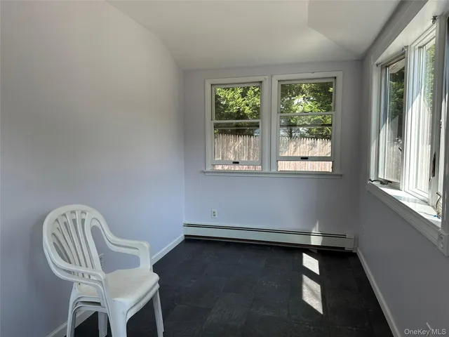 a view of empty room with wooden floor and kitchen view