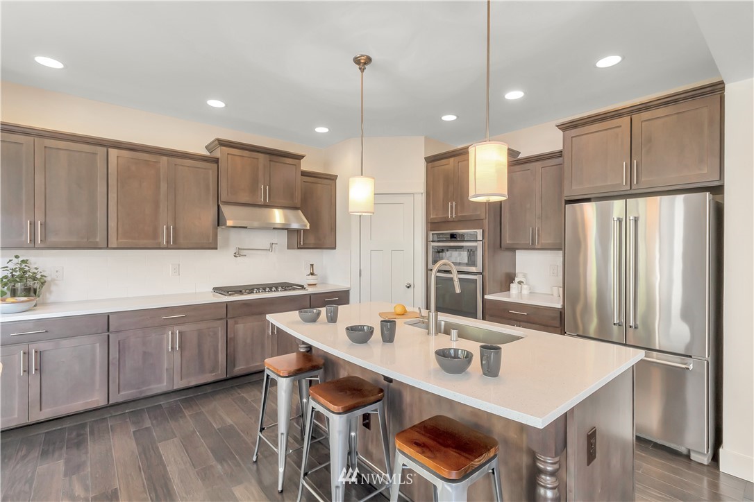4431 225th Place Southeast Bothell, WA 98021 - Photo 6 of 19 a kitchen with stainless steel appliances granite countertop a sink a stove a refrigerator and island with wooden floor