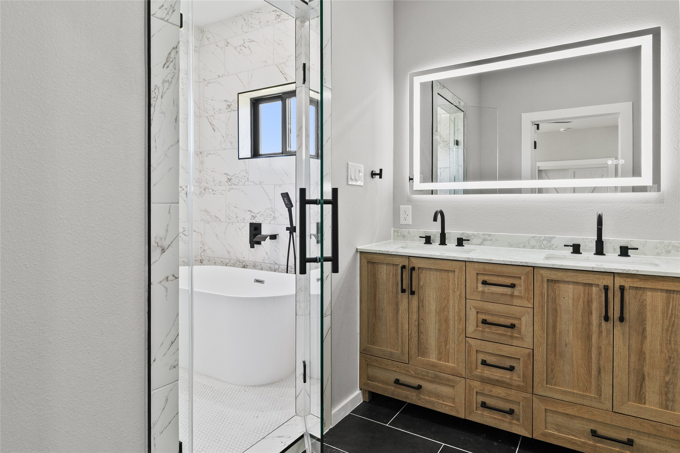 619 Chuckwagon Trail Angleton, TX 77515 - Photo 21 of 37 Spa-inspired primary bath featuring a fully tiled wet room with a freestanding soaking tub, dual shower heads, double vanities, illuminated mirror, and a private water closet. Thoughtfully designed with both style and functionality in mind.