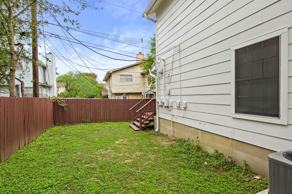 2102 Kenneth Avenue, Unit A Austin, TX 78741 - Photo 14 of 15 Expansive backyard featuring a lush green lawn, a privacy fence, exterior stairs, and a white siding facade