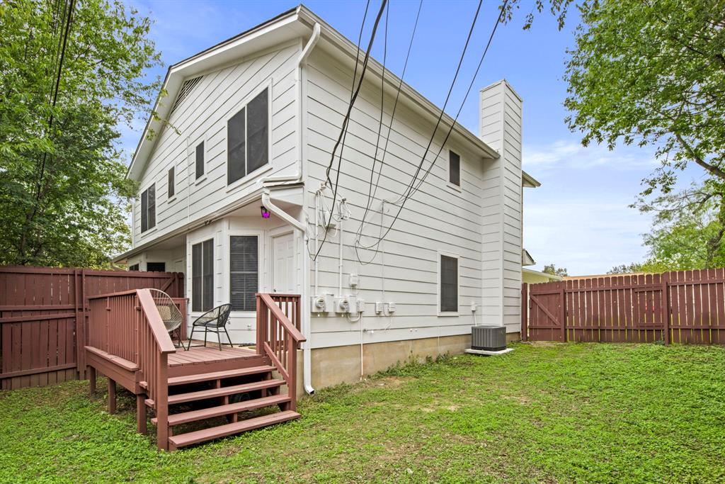 2102 Kenneth Avenue, Unit A Austin, TX 78741 - Photo 15 of 15 White siding exterior featuring a multi-level deck, a private fenced yard, a bay window, and a prominent chimney