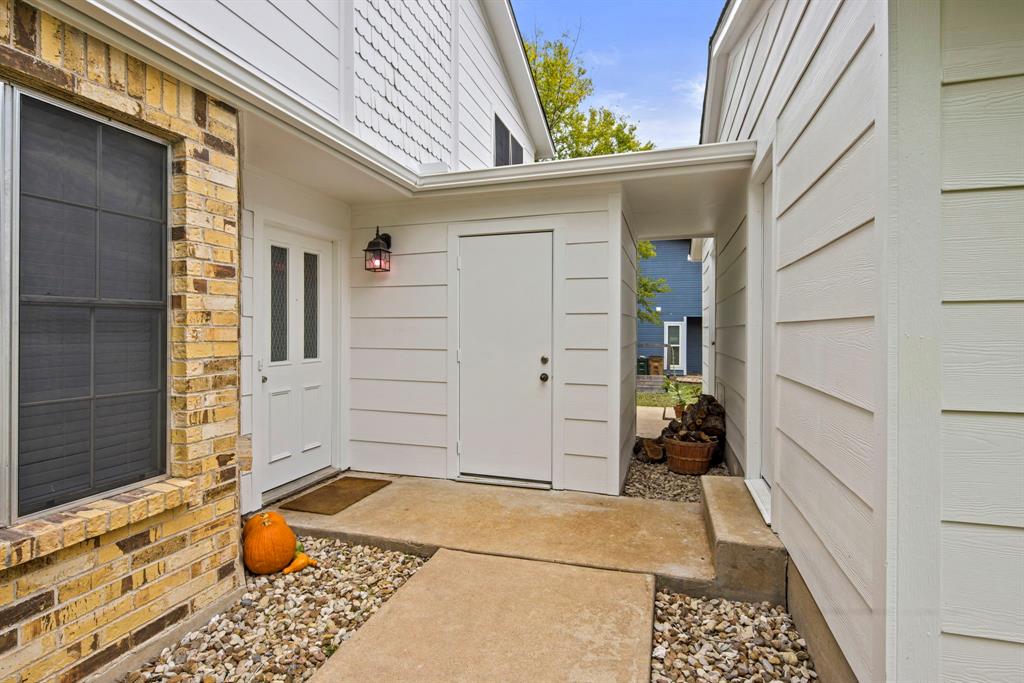 2102 Kenneth Avenue, Unit A Austin, TX 78741 - Photo 2 of 15 Exterior entry featuring a covered porch, white paneled siding, a brick facade, and a white front door with vertical windows