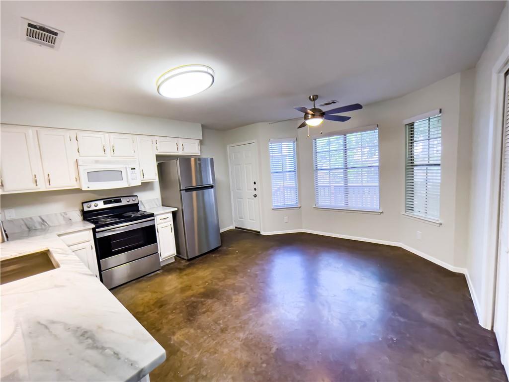 2102 Kenneth Avenue, Unit A Austin, TX 78741 - Photo 6 of 15 Kitchen and living area featuring white cabinetry, stainless steel appliances, marble-look countertops, and concrete flooring