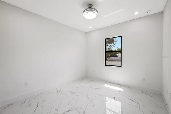 an empty room with a fan & a window