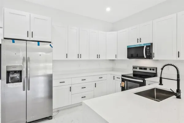 a kitchen with granite countertop white cabinets and stainless steel appliances