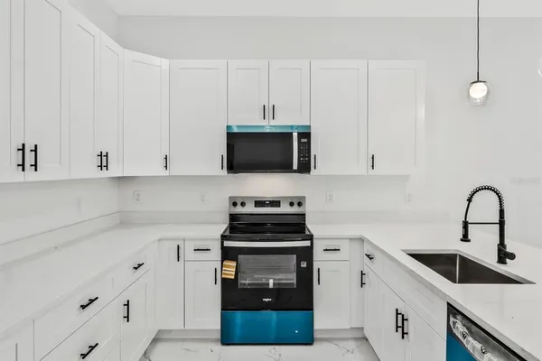 a kitchen with white cabinets and black appliances