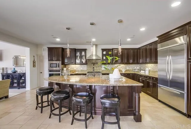 a kitchen with stainless steel appliances granite countertop a stove a refrigerator a oven a sink a table and chairs