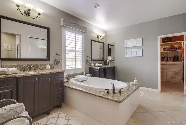 a bathroom with a granite countertop tub shower and mirror