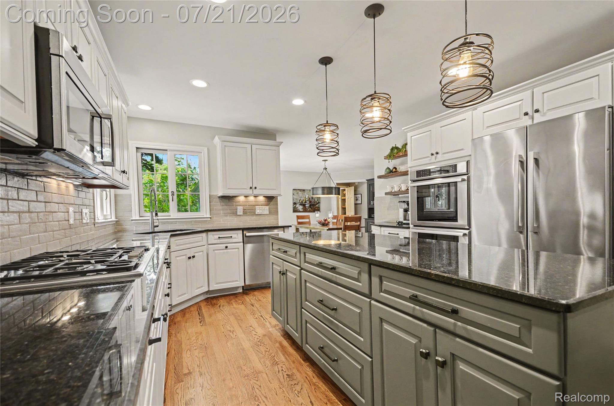 3780 Squirrel Road Bloomfield Hills, MI 48304 - Photo 13 of 59 Gourmet kitchen featuring a central island with dark countertops, stainless steel appliances, white perimeter cabinetry, and wood-finish flooring