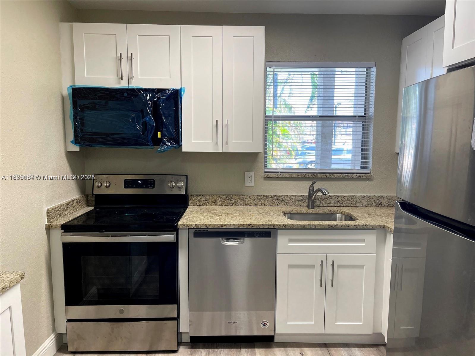 400 Northwest 65th Avenue, Unit 120 Margate, FL 33063 - Photo 6 of 17 a kitchen with granite countertop a stove a sink and a microwave