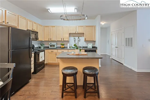 a kitchen with stainless steel appliances granite countertop a stove a refrigerator a oven a sink a island with a dining table and chairs