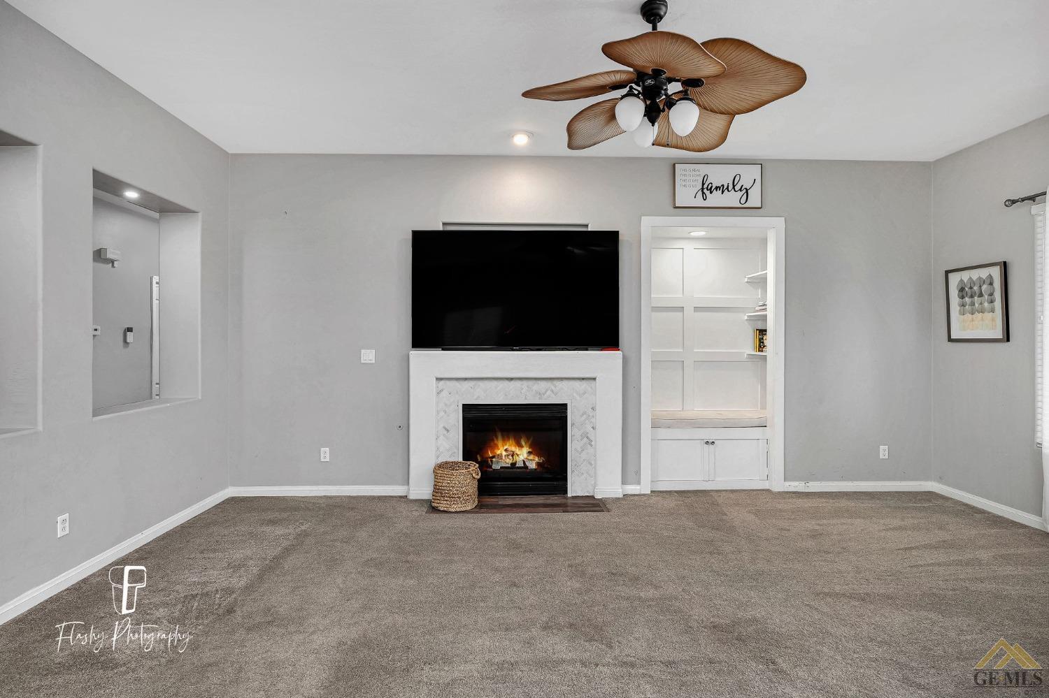 Undisclosed Address Bakersfield, CA 93311 - Photo 19 of 55 a view of a livingroom with a fireplace a chandelier fan and windows