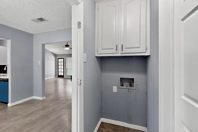 a view of a hallway with wooden floor and a cabinet
