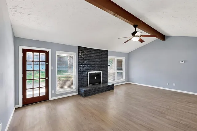 wooden floor fireplace and windows in an empty room