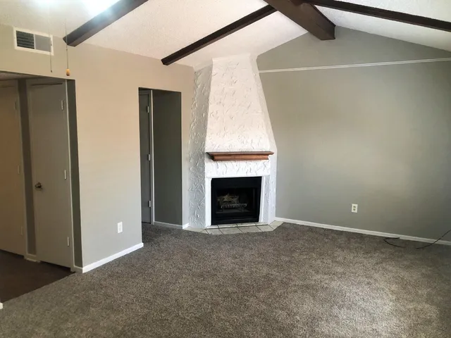 a view of an empty room with a fireplace and a window