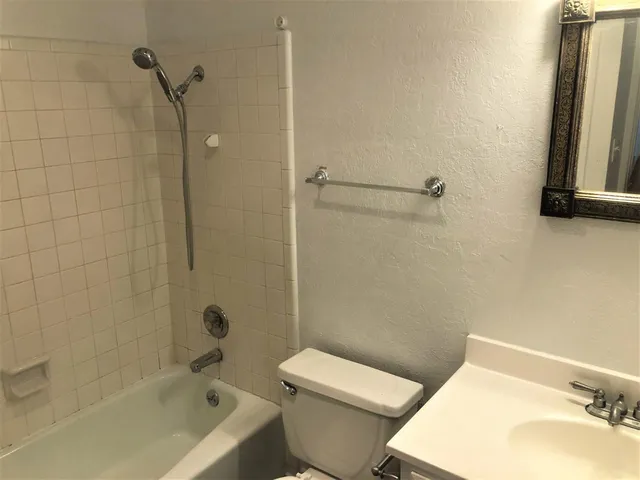 a white toilet sitting next to a bath tub and a shower