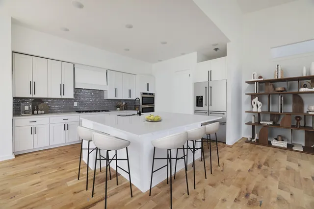 a kitchen with stainless steel appliances granite countertop a table chairs and a refrigerator