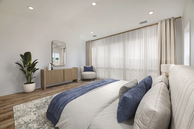 a spacious bedroom with a large bed and a potted plant