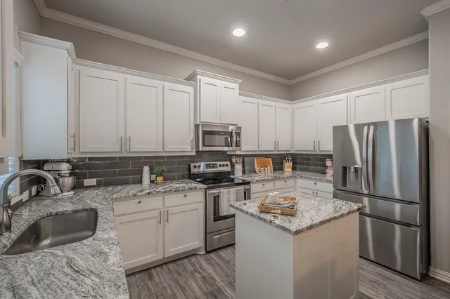 a kitchen with stainless steel appliances granite countertop a sink stove refrigerator and cabinets