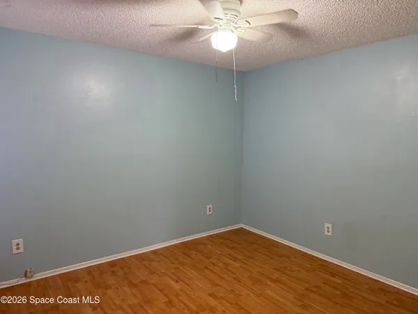 en empty room with wooden floor and fan