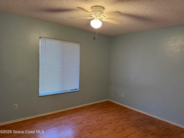 an empty room with wooden floor chandelier fan and windows