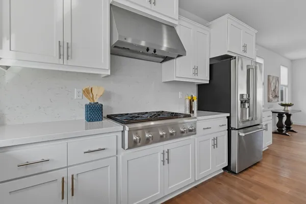 a kitchen with a sink a stove a refrigerator and white cabinets