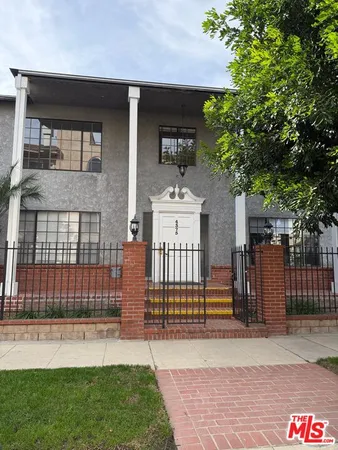 a view of a house with a small yard and wooden fence