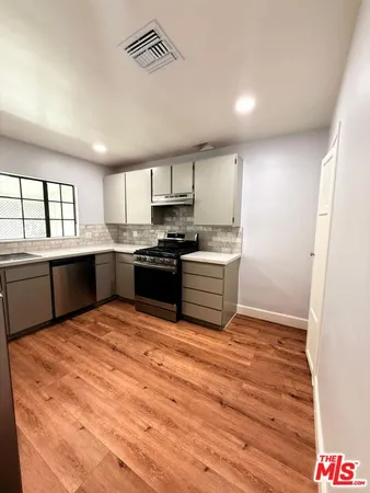a large kitchen with wooden floors and stainless steel appliances
