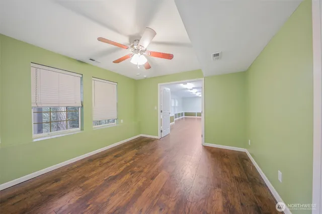 a view of empty room with wooden floor and fan