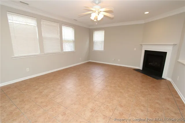 an empty room with windows and ceiling fan